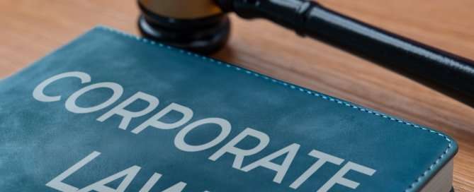 A book on a wooden table with title CORPORATE LAW and a gavel. Legal and business concepts.